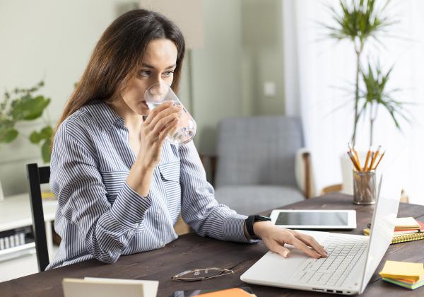 Young business woman working in home office drinking water
