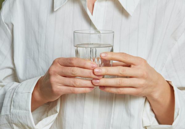 Lady holding a glass of water that has been filled at a plumbed in water cooler